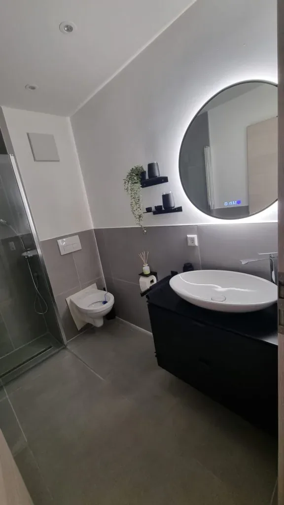 Modernes Badezimmer mit schwarzem Waschtisch und Lichtspiegel